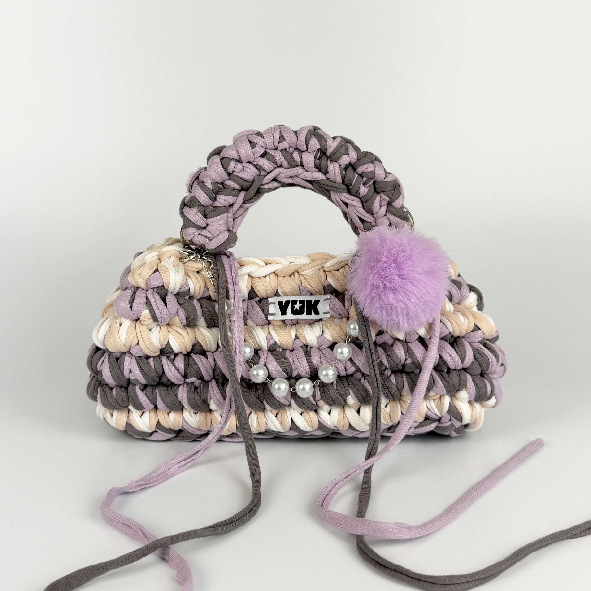 Handmade crochet handbag in lilac, purple, grey, white and beige with a bag charm by Studio YUK