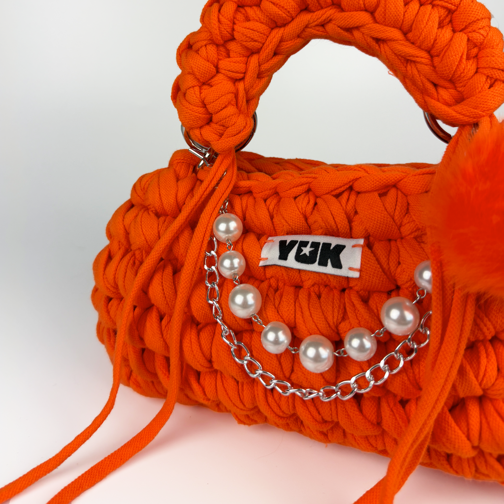 Handmade crochet handbag in oraneg with a bag charm by Studio YUK