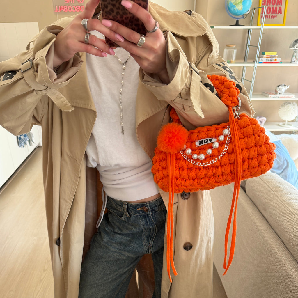Lifestyle image featuring the orange Studio YUK crochet handbag
