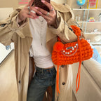 Lifestyle image featuring the orange Studio YUK crochet handbag