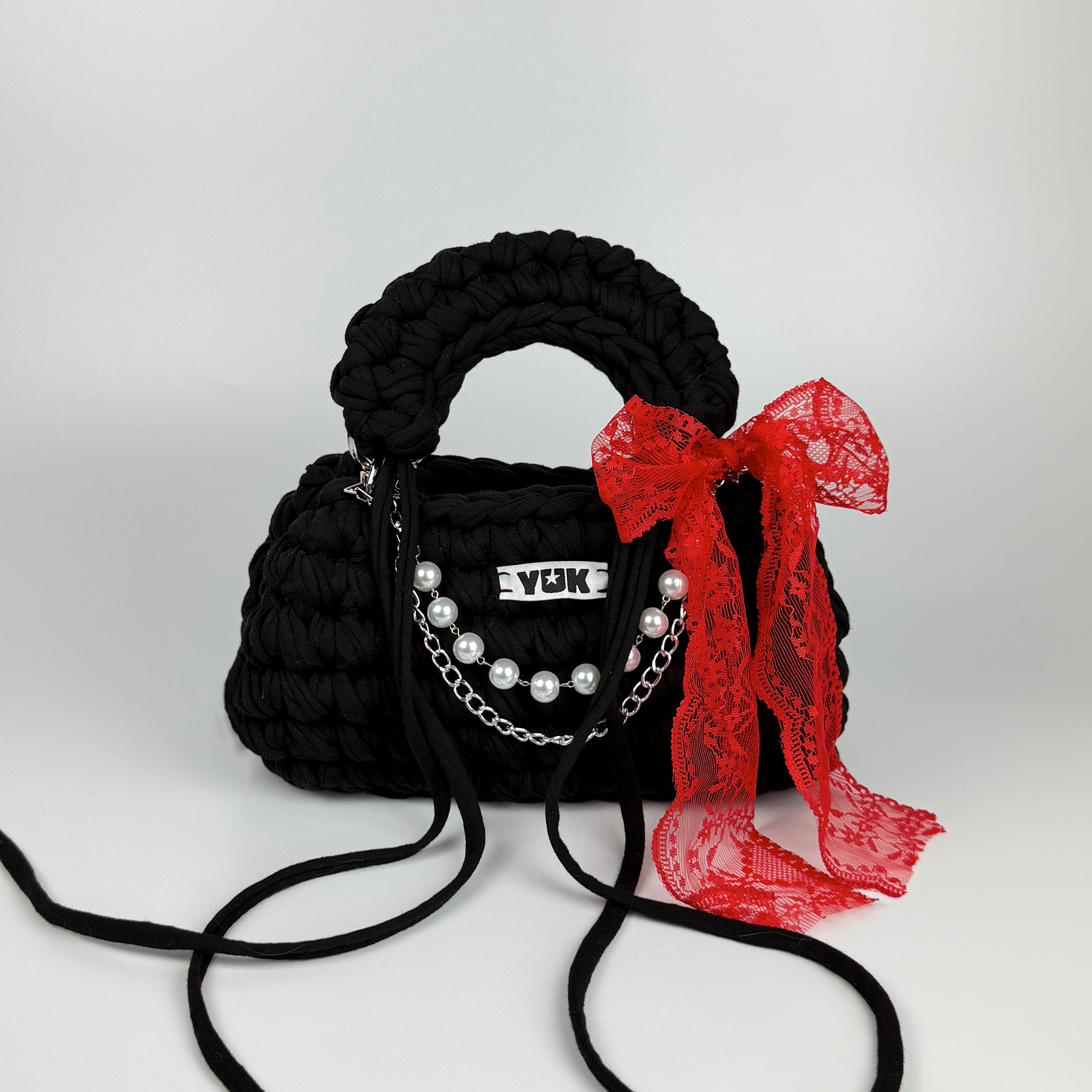 Handmade crochet handbag in blackn with red lace detail and a bag charm by Studio YUK