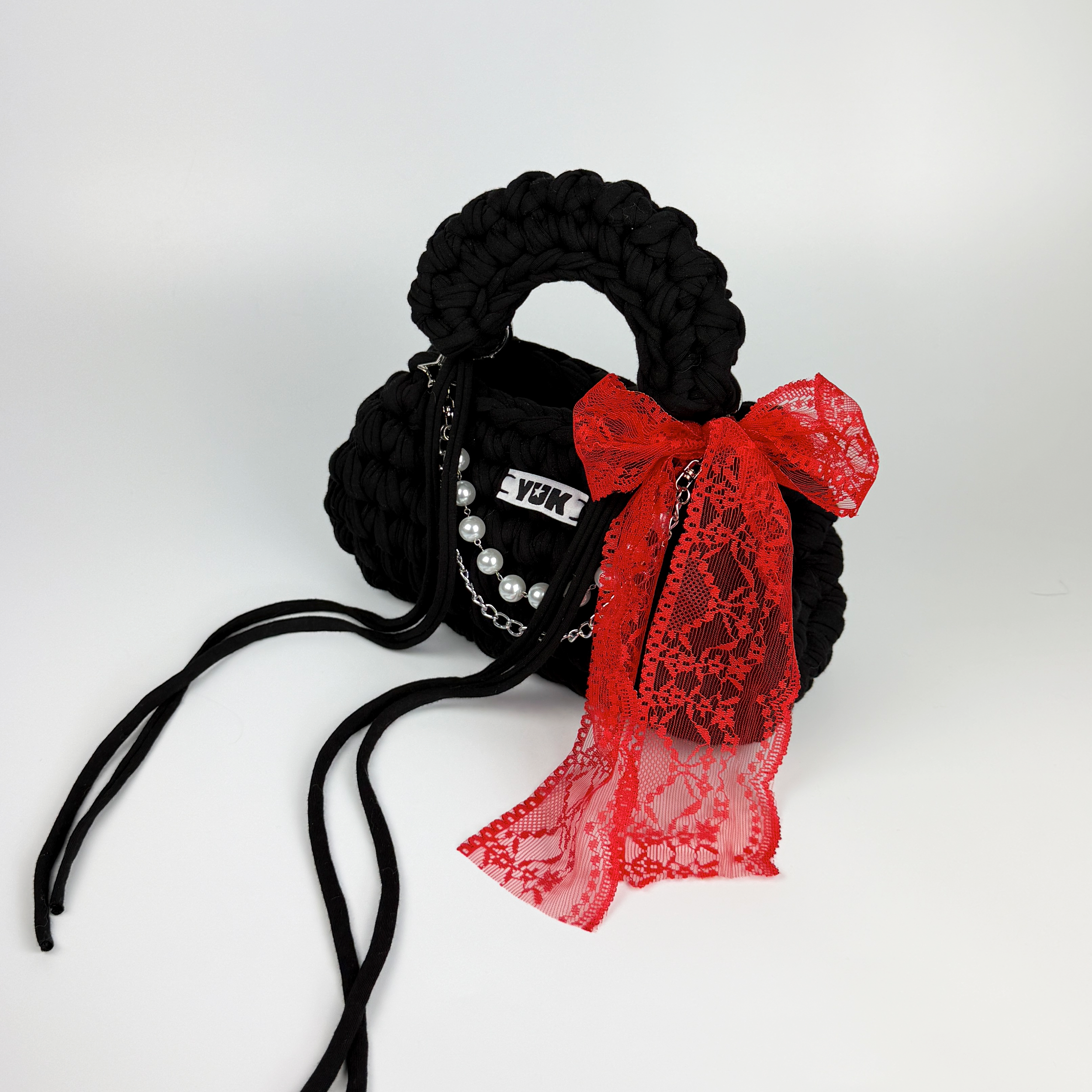 Handmade crochet handbag in blackn with red lace detail and a bag charm by Studio YUK