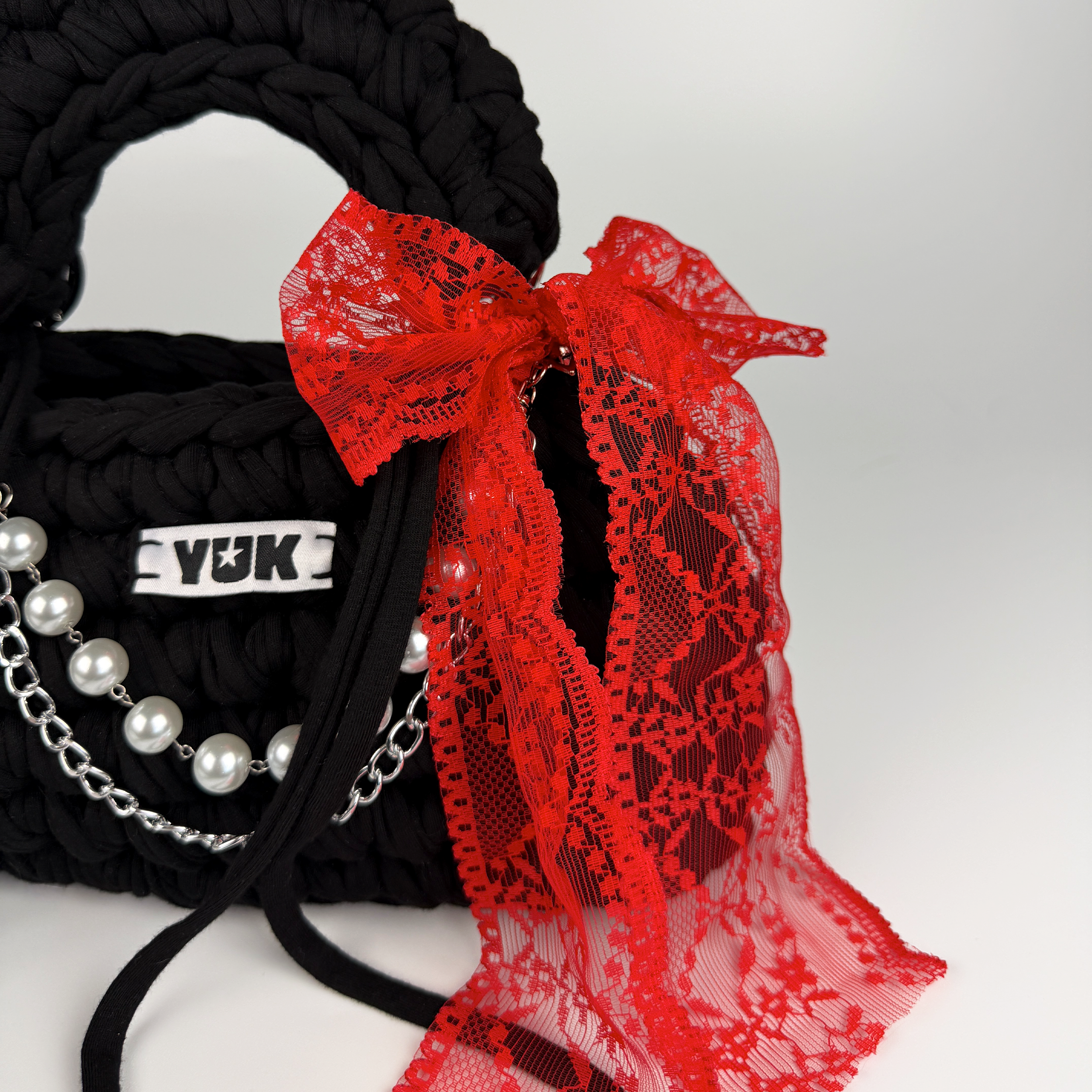 Handmade crochet handbag in blackn with red lace detail and a bag charm by Studio YUK