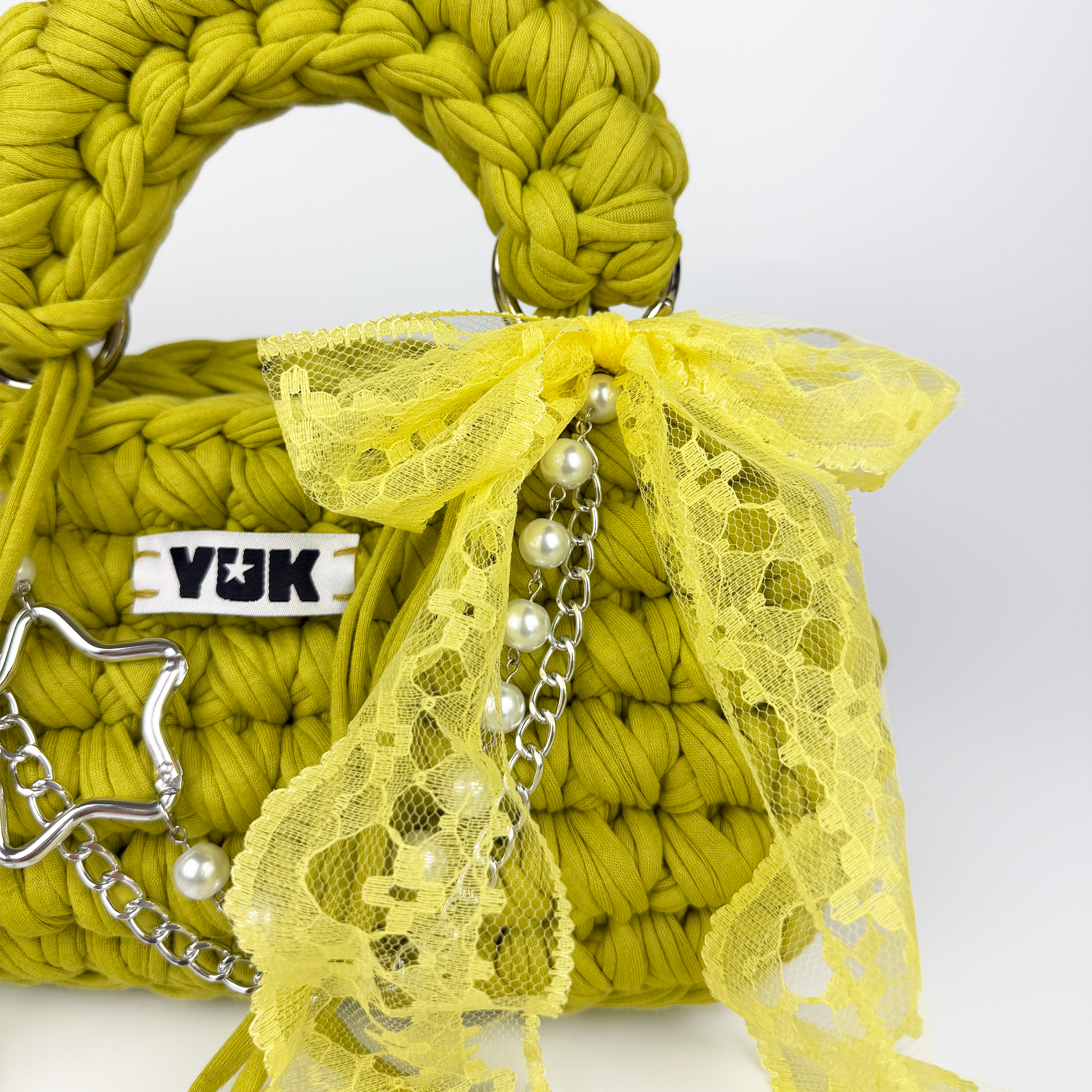 Handmade crochet handbag in green and yellow with lace detail and a bag charm by Studio YUK