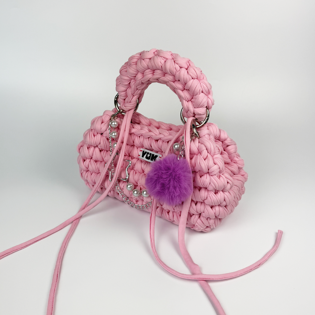 Handmade crochet handbag in pink with pompom detail and a bag charm by Studio YUK