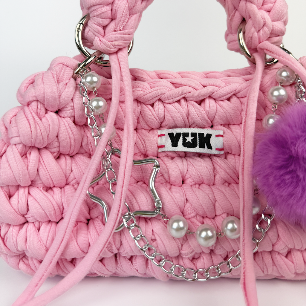 Handmade crochet handbag in pink with pompom detail and a bag charm by Studio YUK